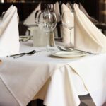 Restoranski stol sa bijelim stolnjakom i urednom postavom