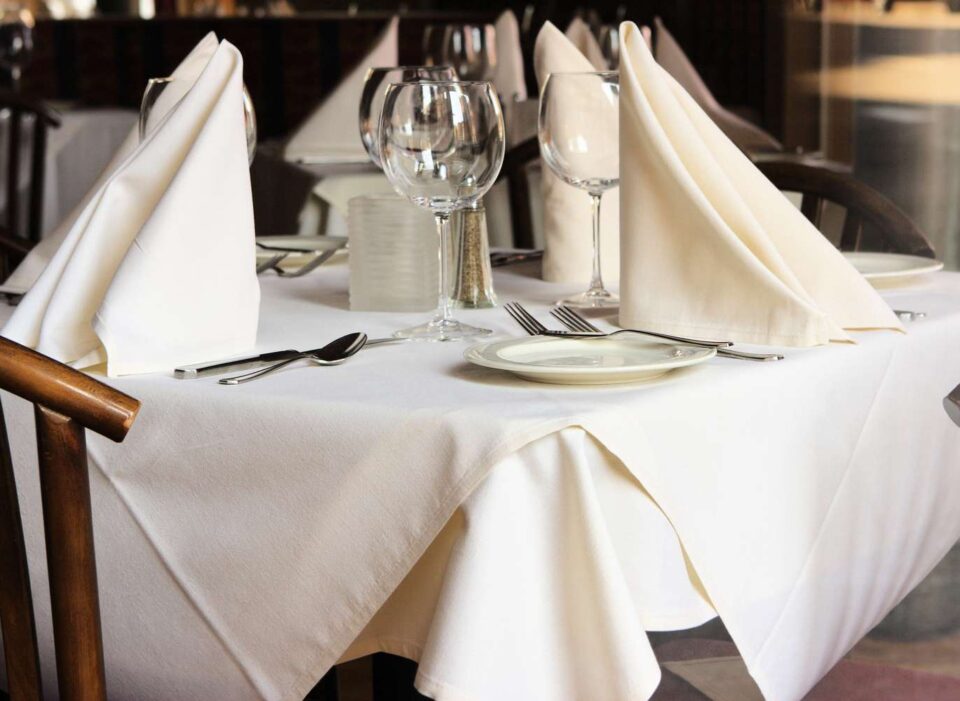 Restoranski stol sa bijelim stolnjakom i urednom postavom